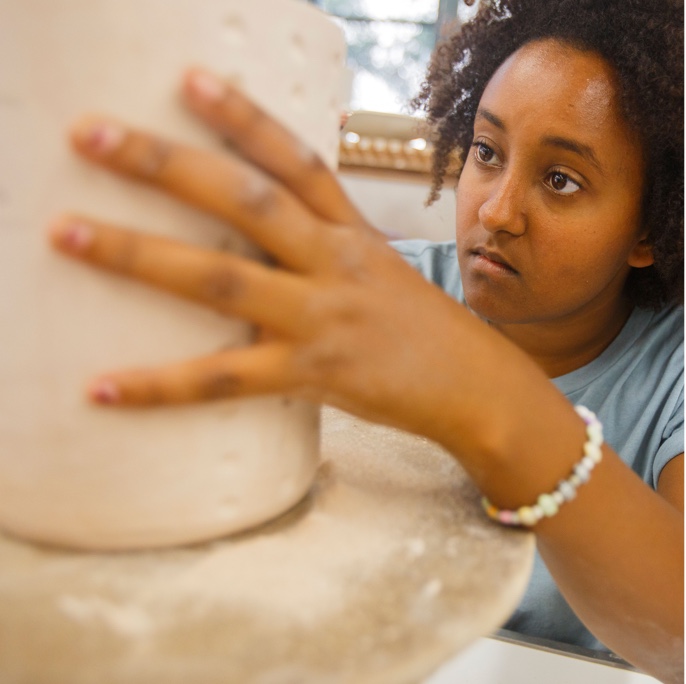 Pottery student spinning clay